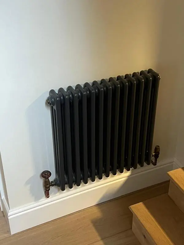 Dark column radiator installed on staircase landing